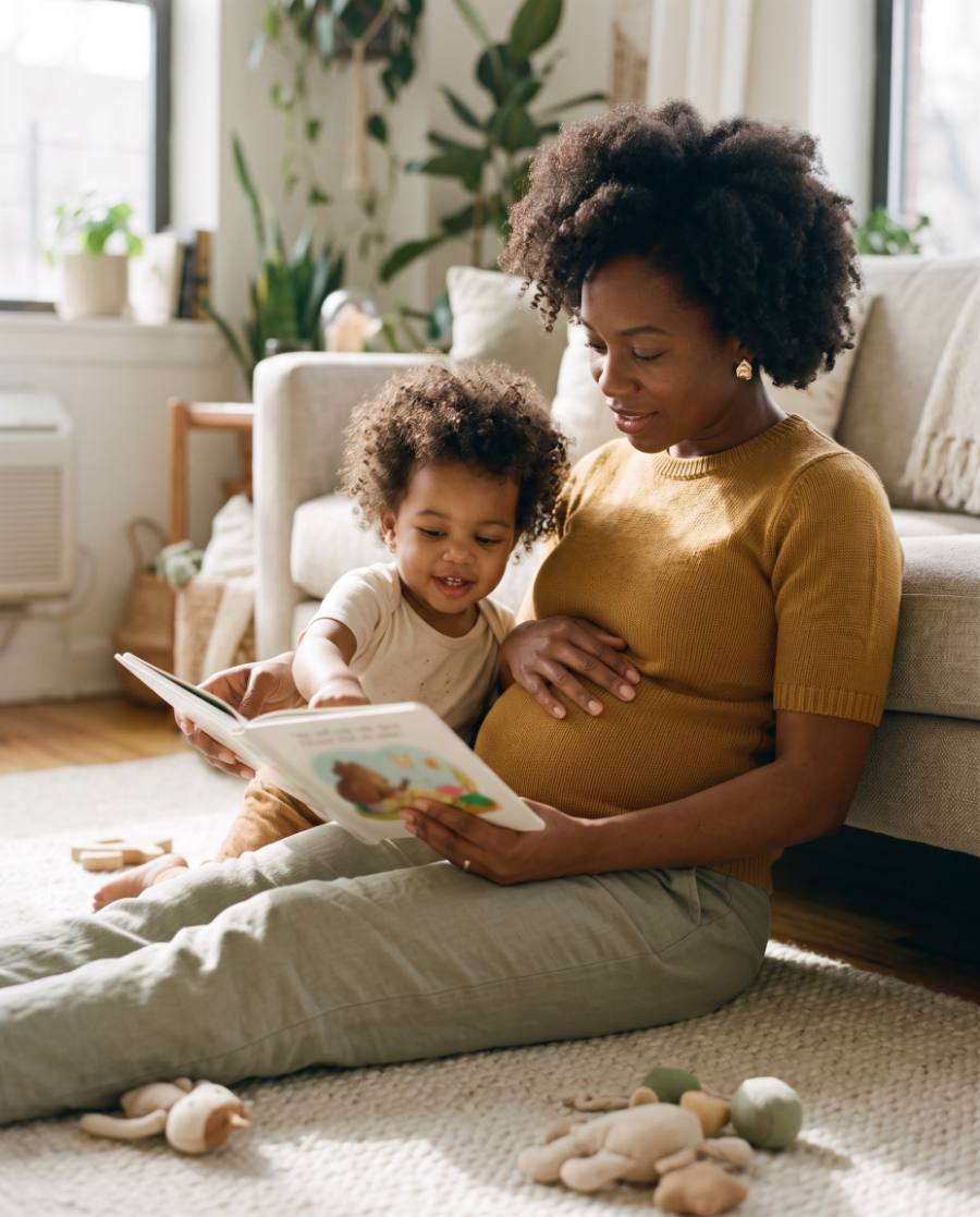 A pregnant woman at home with her toddler on her lap